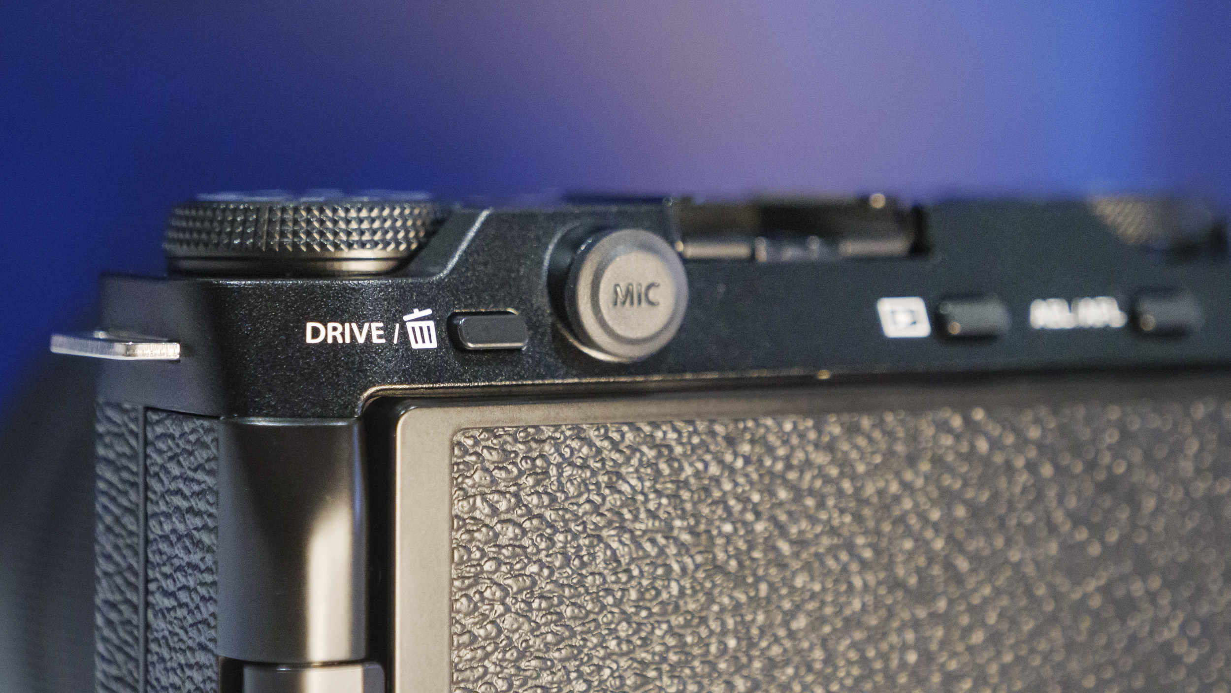 Closeup of the mic port of the Fujifilm X-M5 camera, with rich blue background