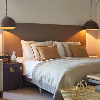 bedroom with hanging lamp and cushions on bed
