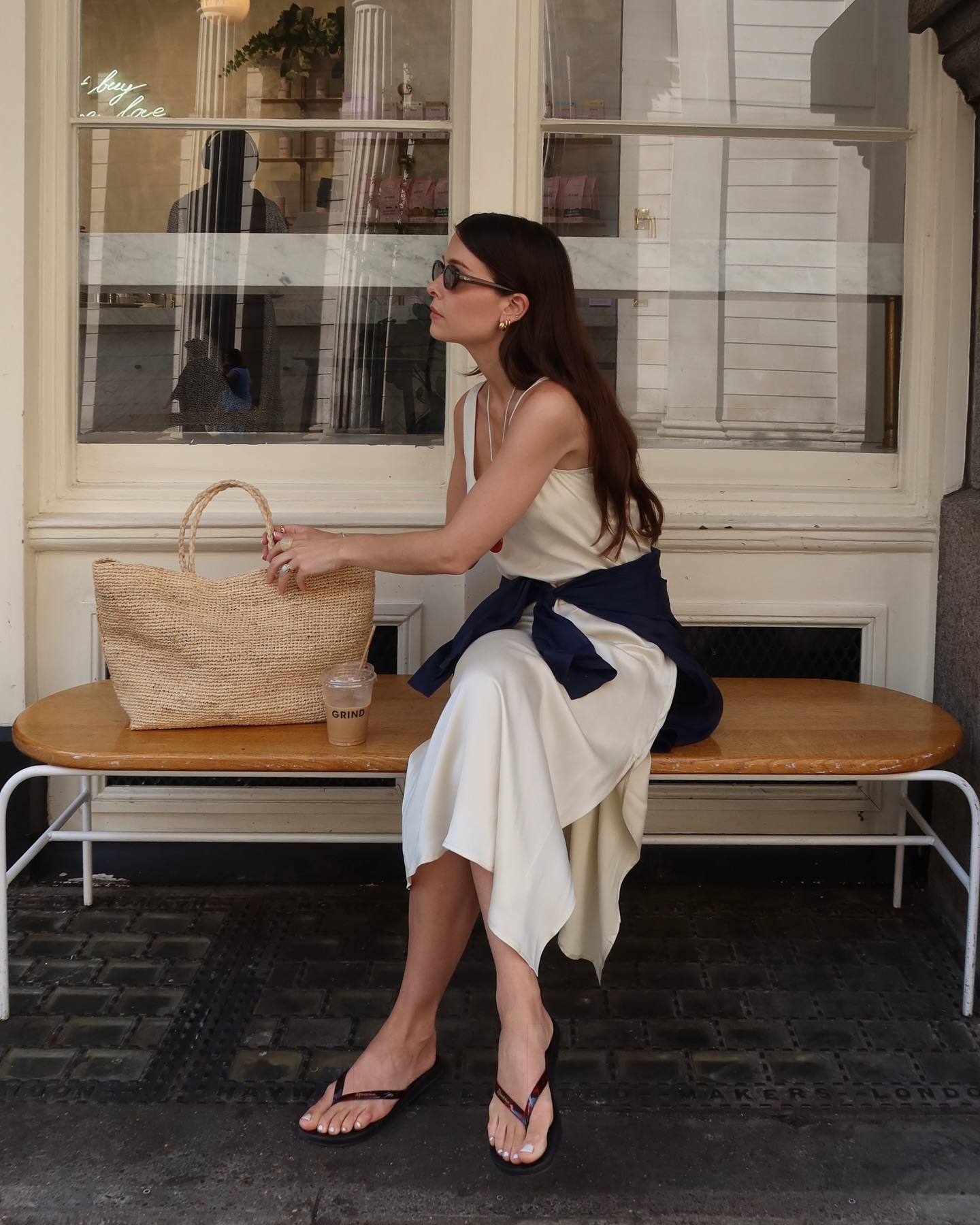 the alice edit wears a satin slip dress, flip flops and a basket bag
