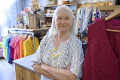 Portrait Of Senior Female Volunteer Working In Charity Shop Or Thrift Store Selling Used And Sustainable Clothing