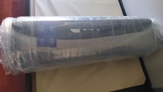 Nectar mattress rolled up in plastic on a platform bed