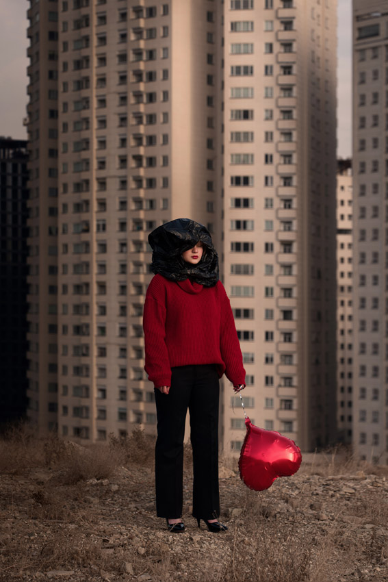 Photograph of a woman carrying a red heart balloon standing in front of a tower block and titled Lost Hope. Captured by Siavosh Ejlali from the Islamic Republic of Iran, this photograph won the Creative category in the Open competition of the Sony World Photography Awards 2026