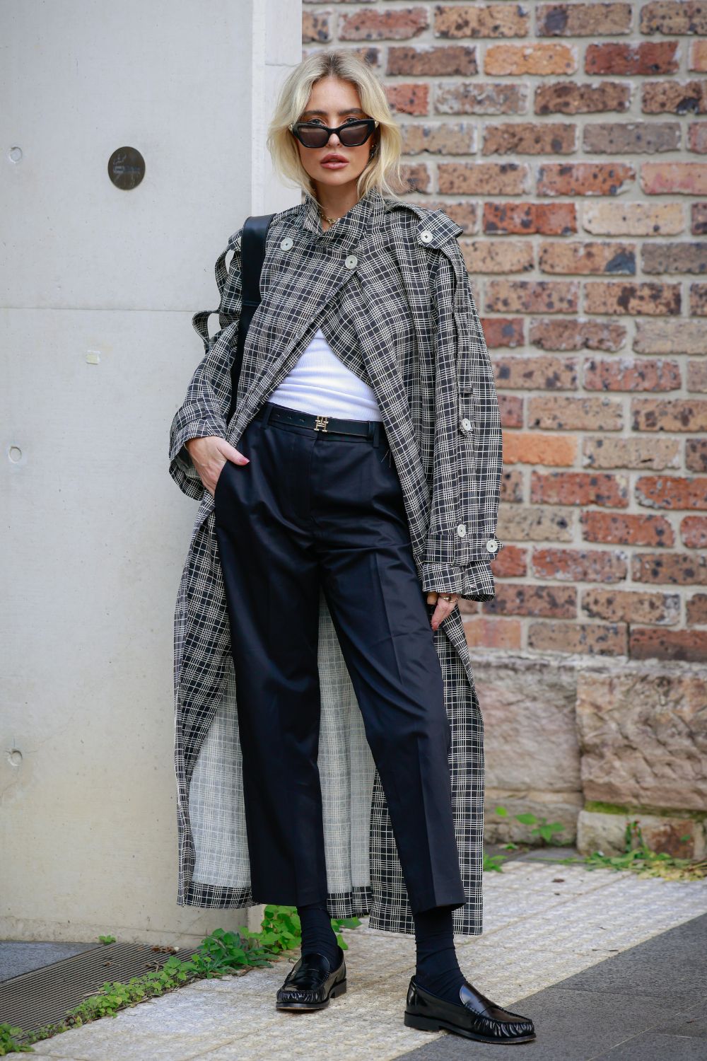 Emily Gurr wearing grey checked trench coat T-shirt, tailored trousers and loafers