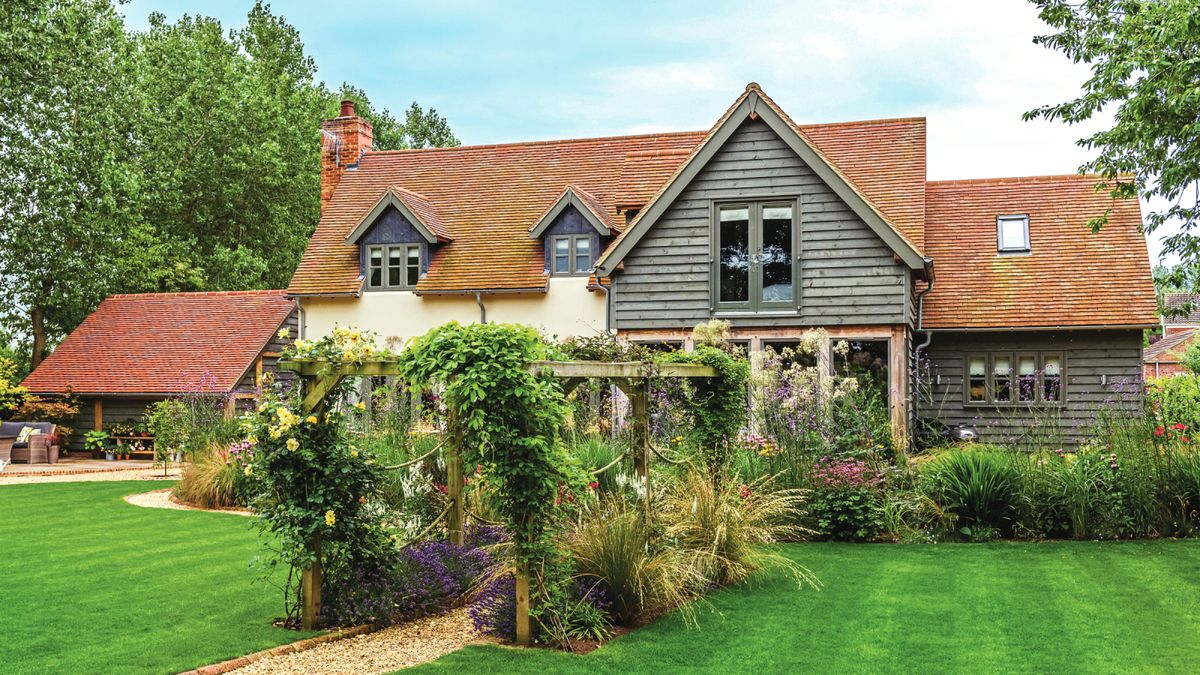 house with pitched roof in garden with trees and green lawns