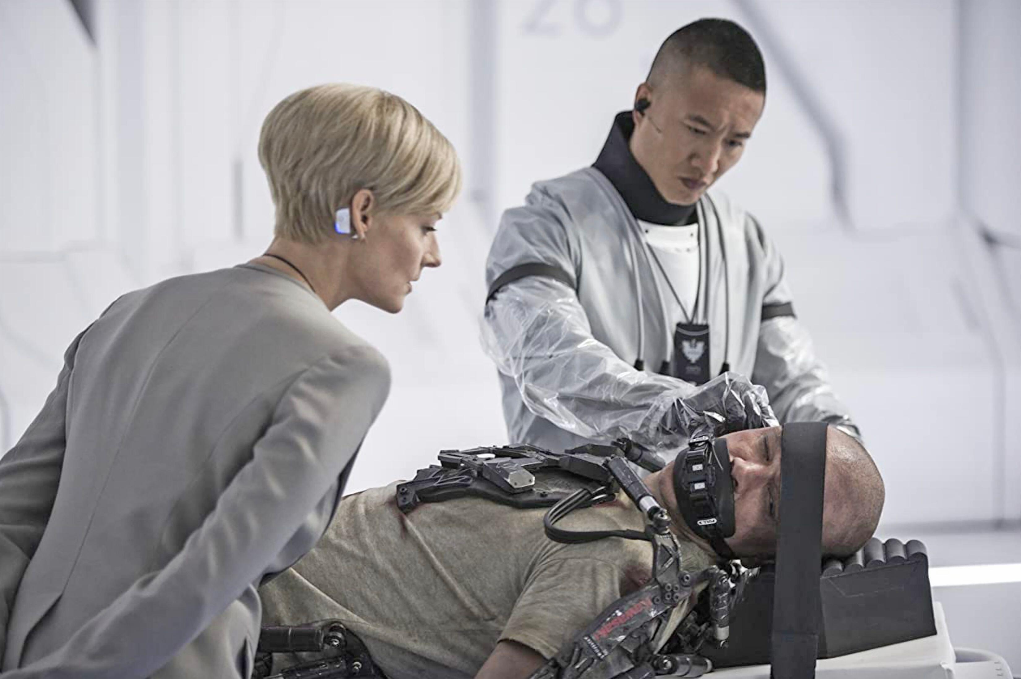 (De gauche à droite) Jodie Foster (en tant que secrétaire à la Défense Jessica Delacourt) regarde Terry Chen (en tant que technicien) opérer Matt Damon (en tant que Max) à Elysium