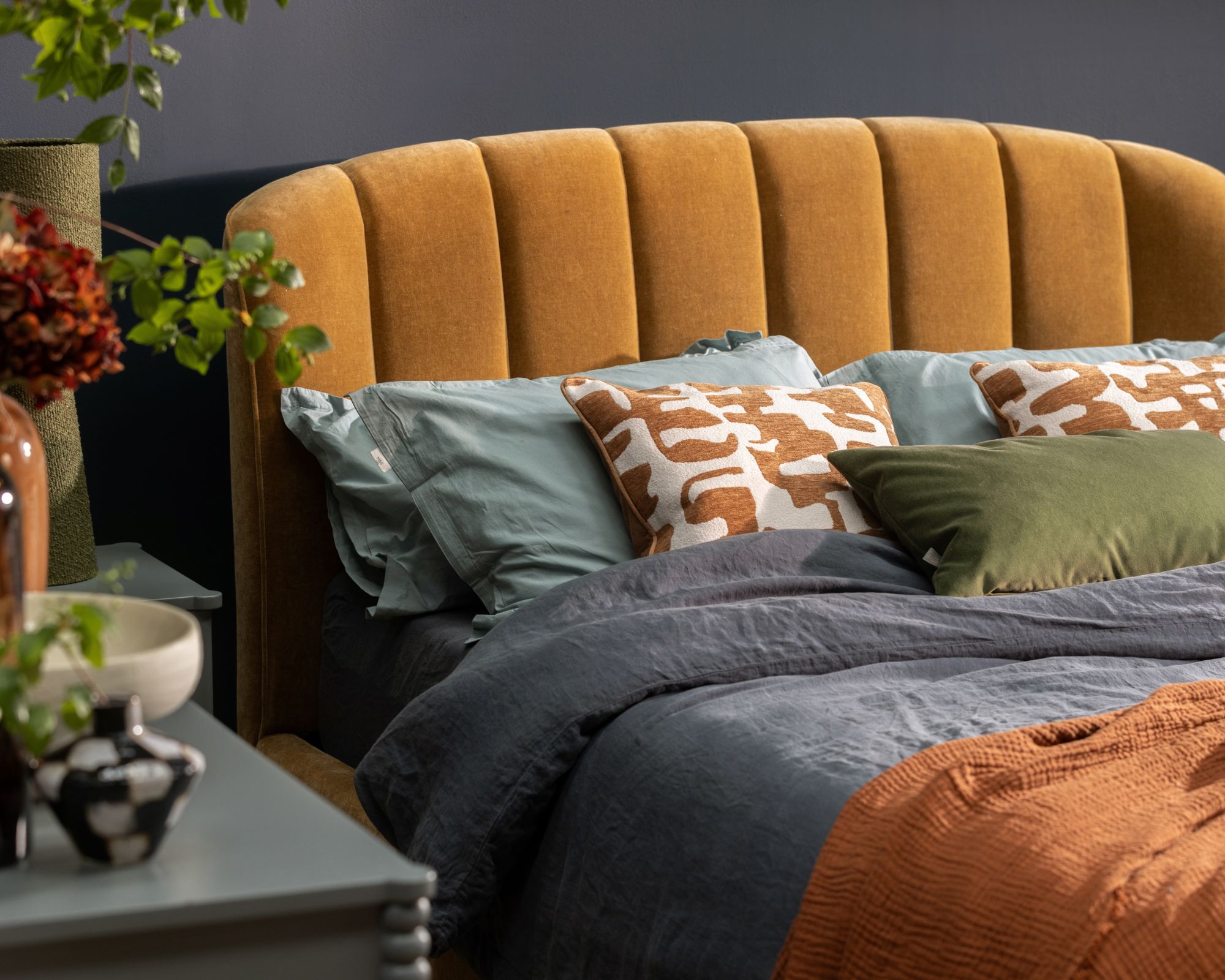 Cozy bed with burnt orange headboard and autumnal bedding