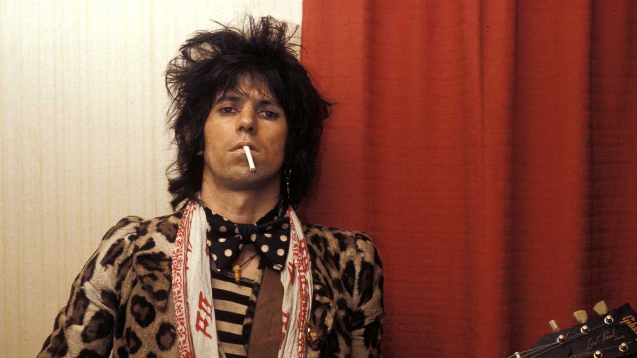Keith Richards smoking a cigarette, holding a guitar