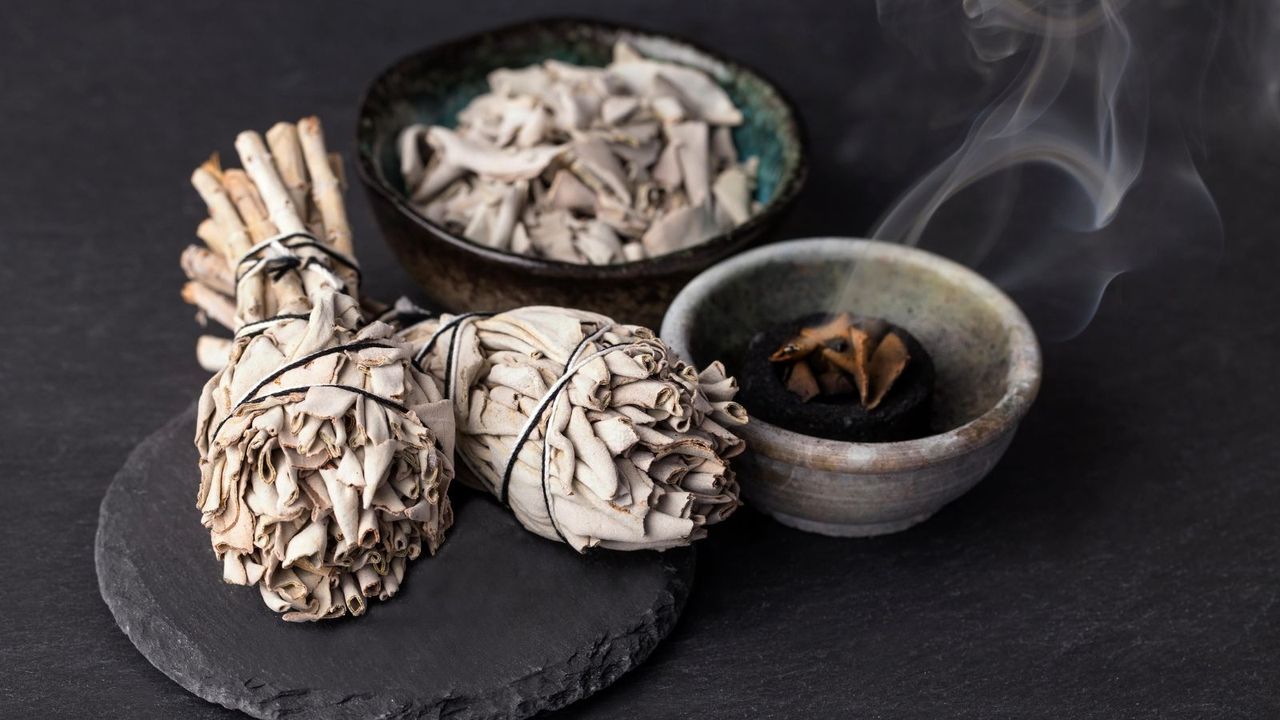 two sage sticks next to a smouldering ramikin