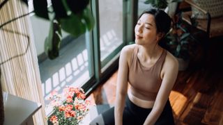 woman sitting next to an open window trying to keep cool