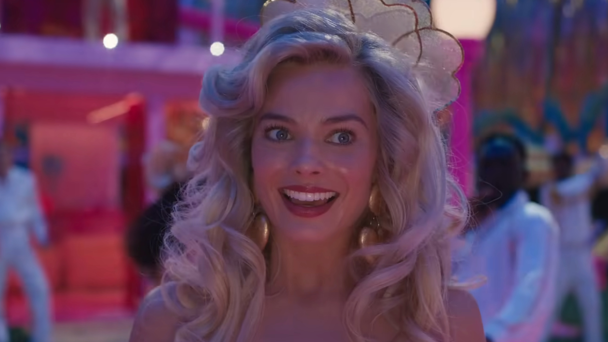 Margot Robbie smiles awkwardly during a scene from the Barbie movie.
