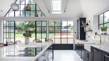 kitchen with vaulted ceiling and steel framed windows and doors gray cabinets and white worktops and flooring