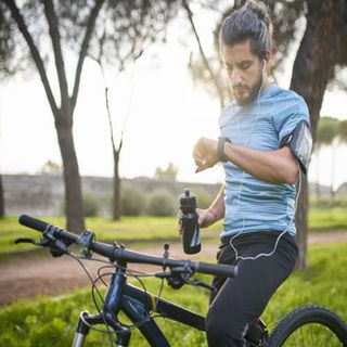 A male cyclist checking his smartwatch on a bike