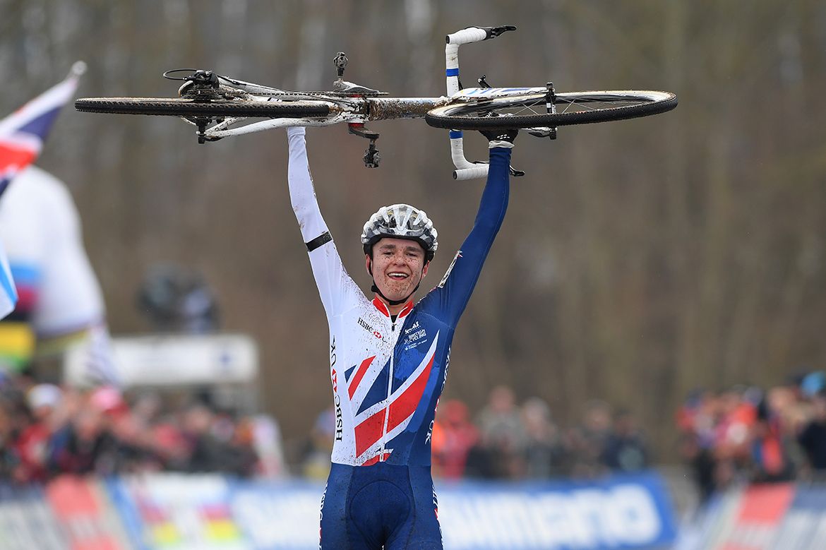 Tom Pidcock lifts his bike above his head