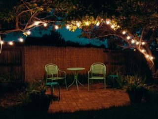 Backyard lighting ideas: image of two green chairs under lights