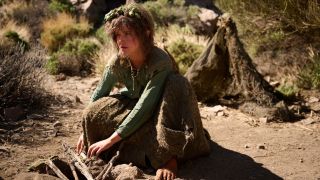 Nori leaning down and touching wood on the ground in Rings of Power.