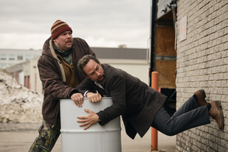 Two men clinging onto a barrel of syrup in The Sticky