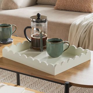 White scalloped tray on coffee table with cafetiere and mug on top