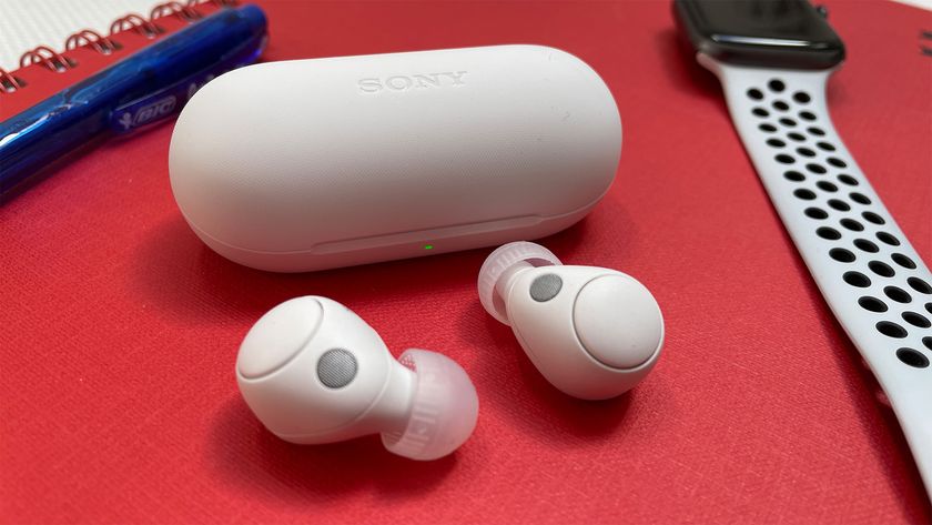  A pair of white Sony WF-C700N next to their carry case and an Apple Watch on a red spiral-bound notebook.