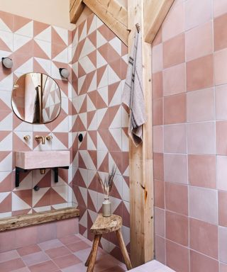 A bathroom with pink and white tiles surrounding exposed wooden wall beams