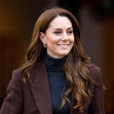 Kate Middleton wears a burgundy coat and a navy turtleneck sweater