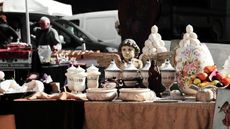 An antiques fair table filled with antique urns, planters, and canisters