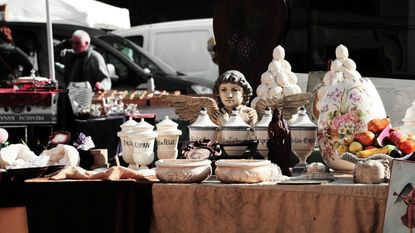 An antiques fair table filled with antique urns, planters, and canisters