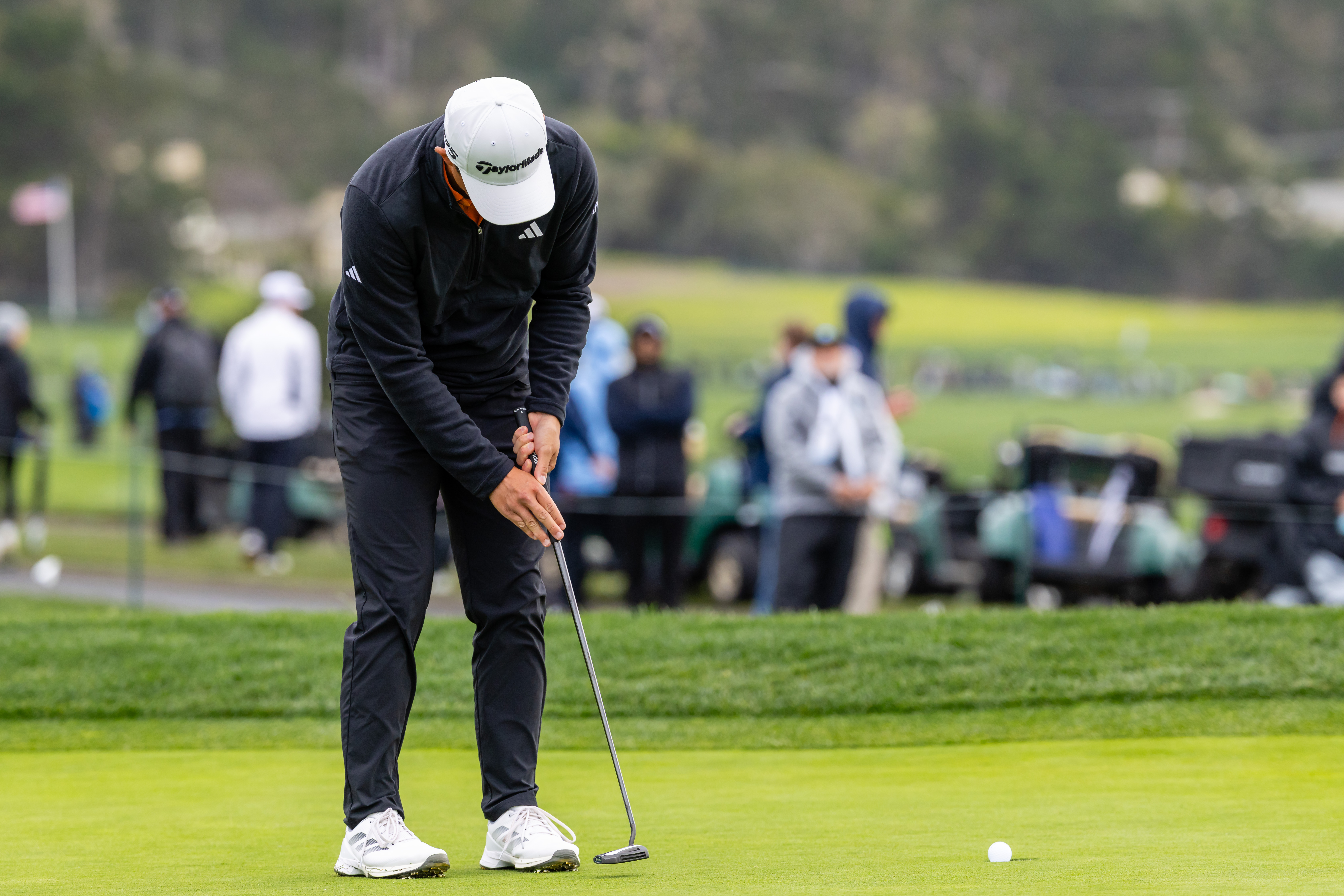 Collin Morikawa hits a putt on the green