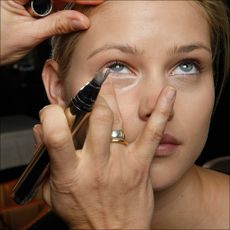 Celebrity makeup artist Pati Dubrof applies under eye concealer to a model's. face