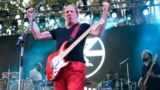 Adrian Belew flexes his muscles onstage with his signature red Strat