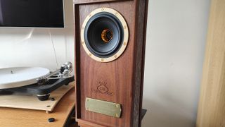 The Tannoy Autograph Mini pictured in a room next to a wooden sideboard and a record player