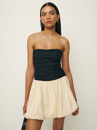Model is wearing a black and white strapless bubble hem dress