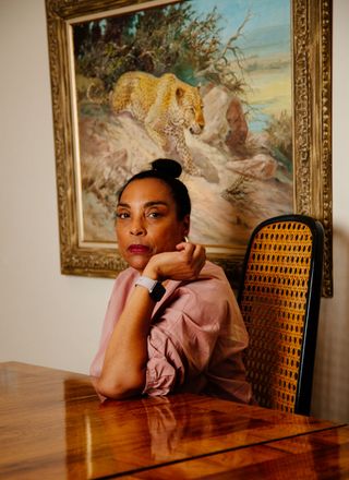 Photo by Olivia Joan of a woman sitting at a table Infront of a painting of a leopard