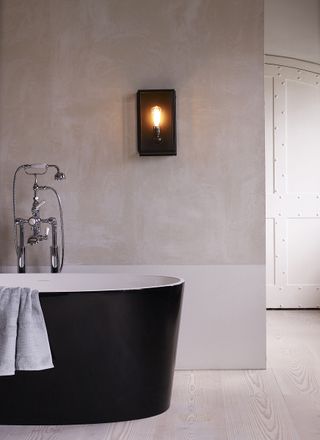 modern bathroom with a luxurious feel, black freestanding bath and concrete finsih walls