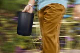 A black Sonos Move 2 being carried by its rear handle.