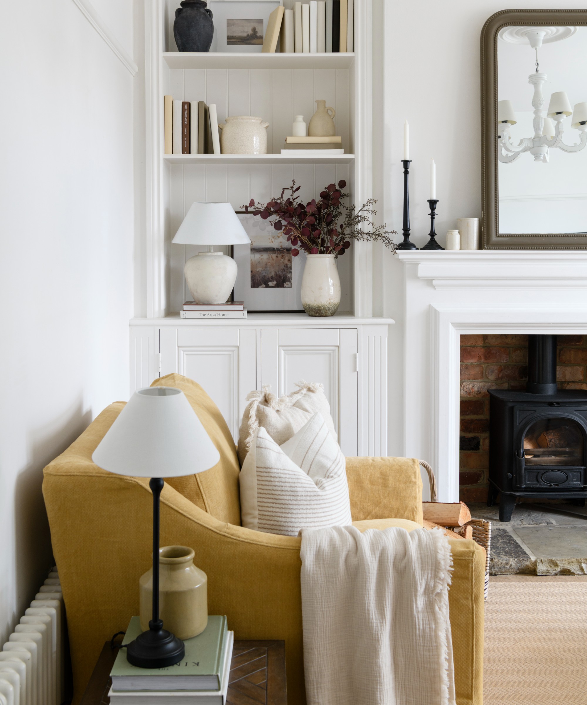 A white living room with a yellow linen armchair and two table lamps