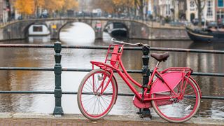 A red bicycle is chained to a bridge in Amsterdam, the Netherlands.