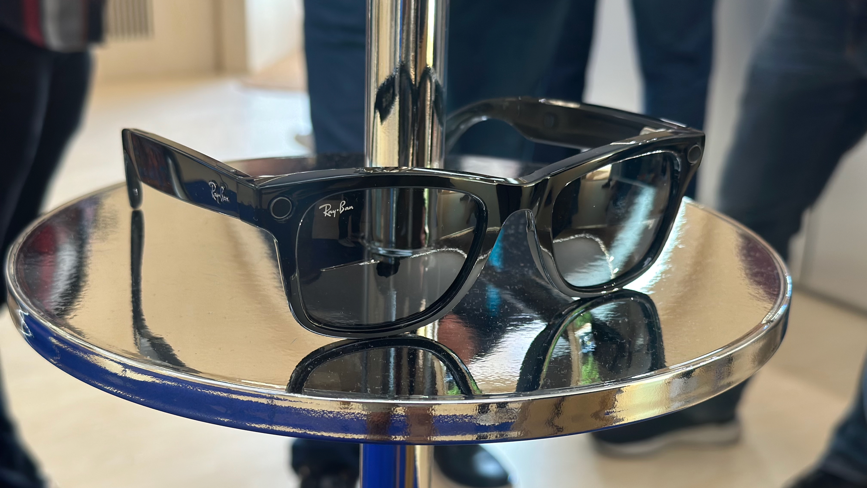 Black Ray-Ban Meta Gen 2 glasses sitting on a metal display shelf.