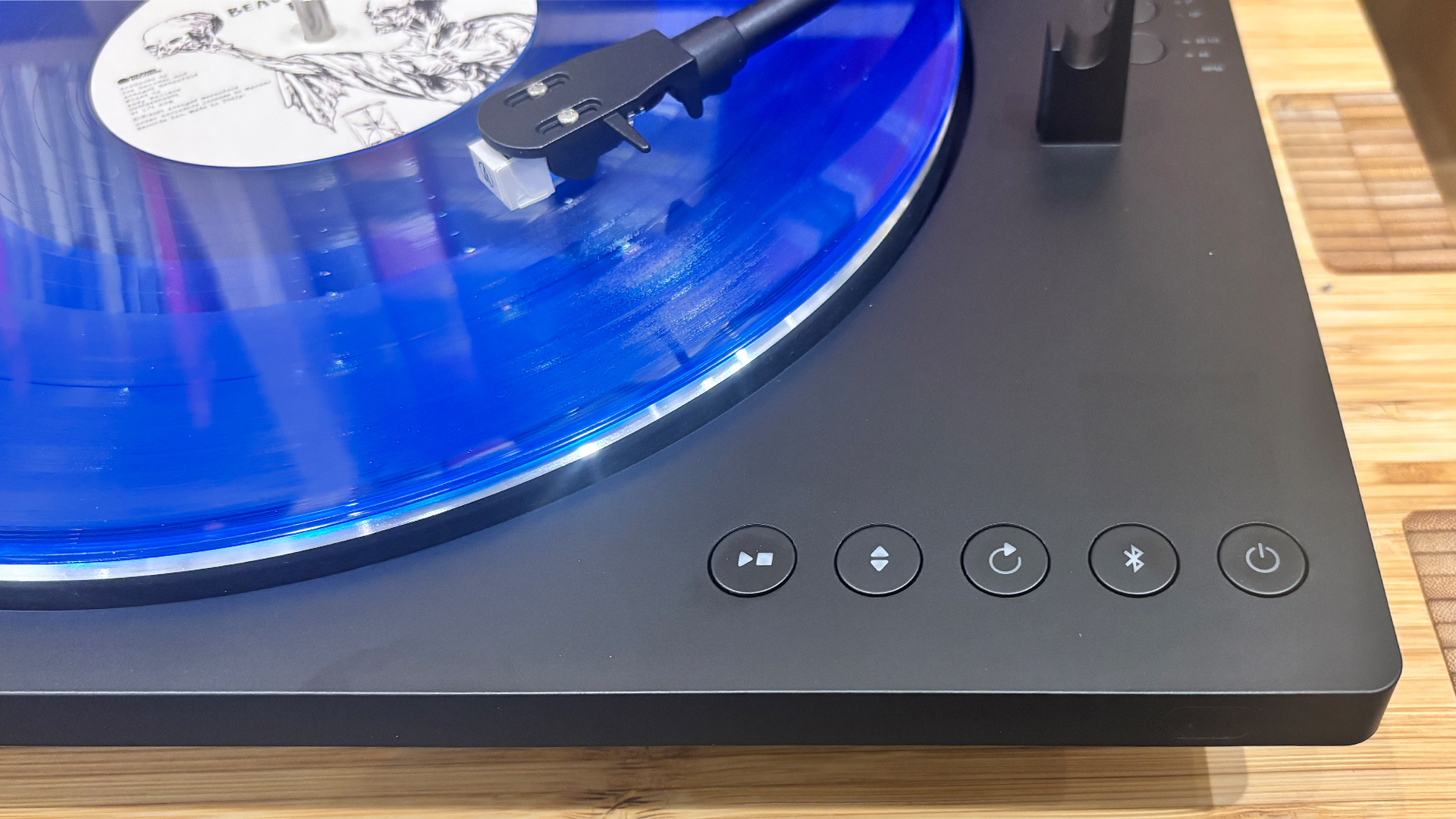 Sharp RP-TT100 Bluetooth turntable playing blue vinyl record, close up on control buttons