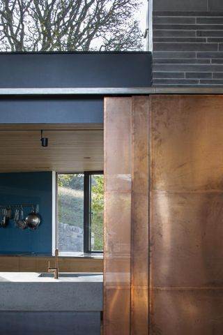 Kitchen counter and basin with copper features and kitchen utensils hanging in background