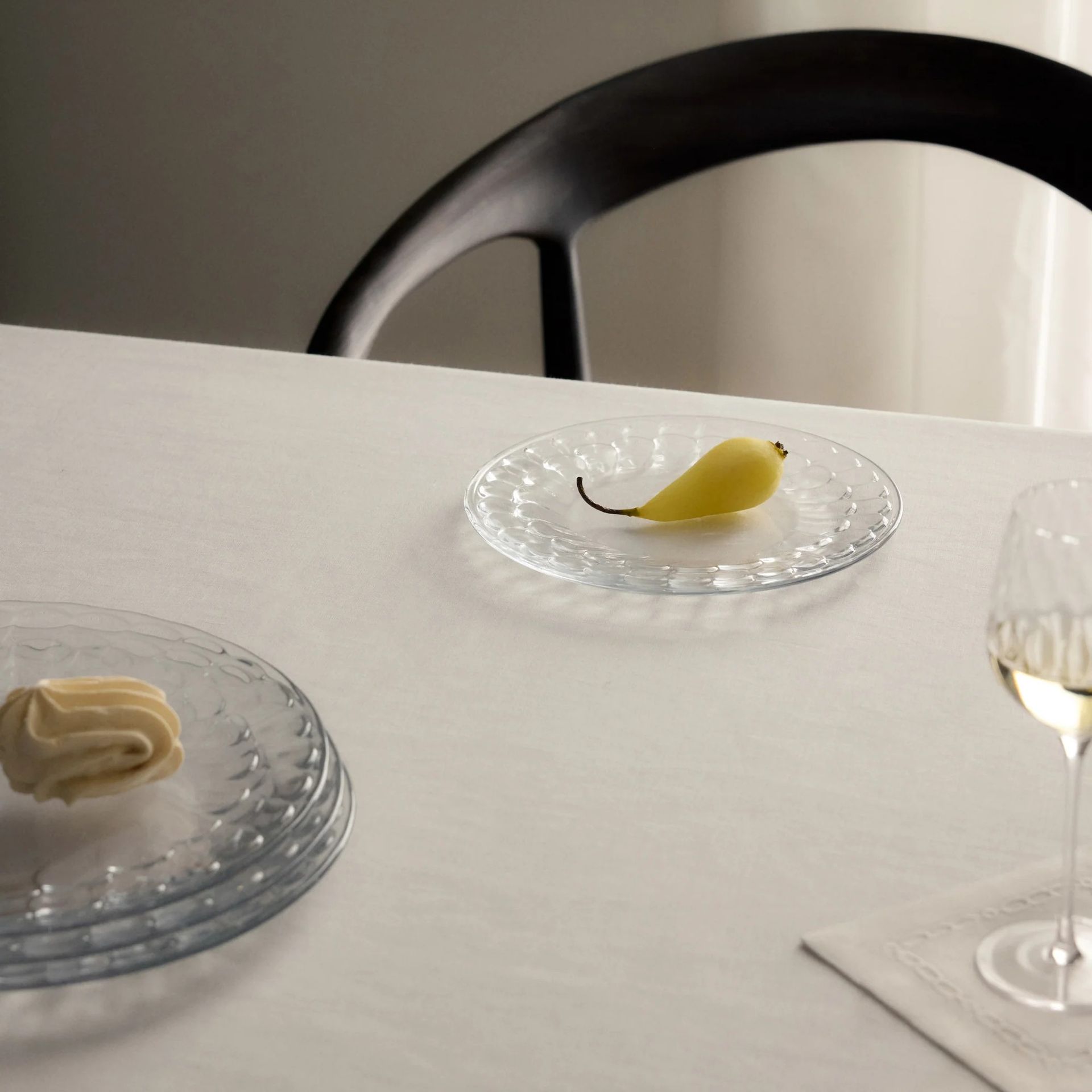 A dining table set with the glass Isla plates from Victoria Beckham's tableware collection with Westwing