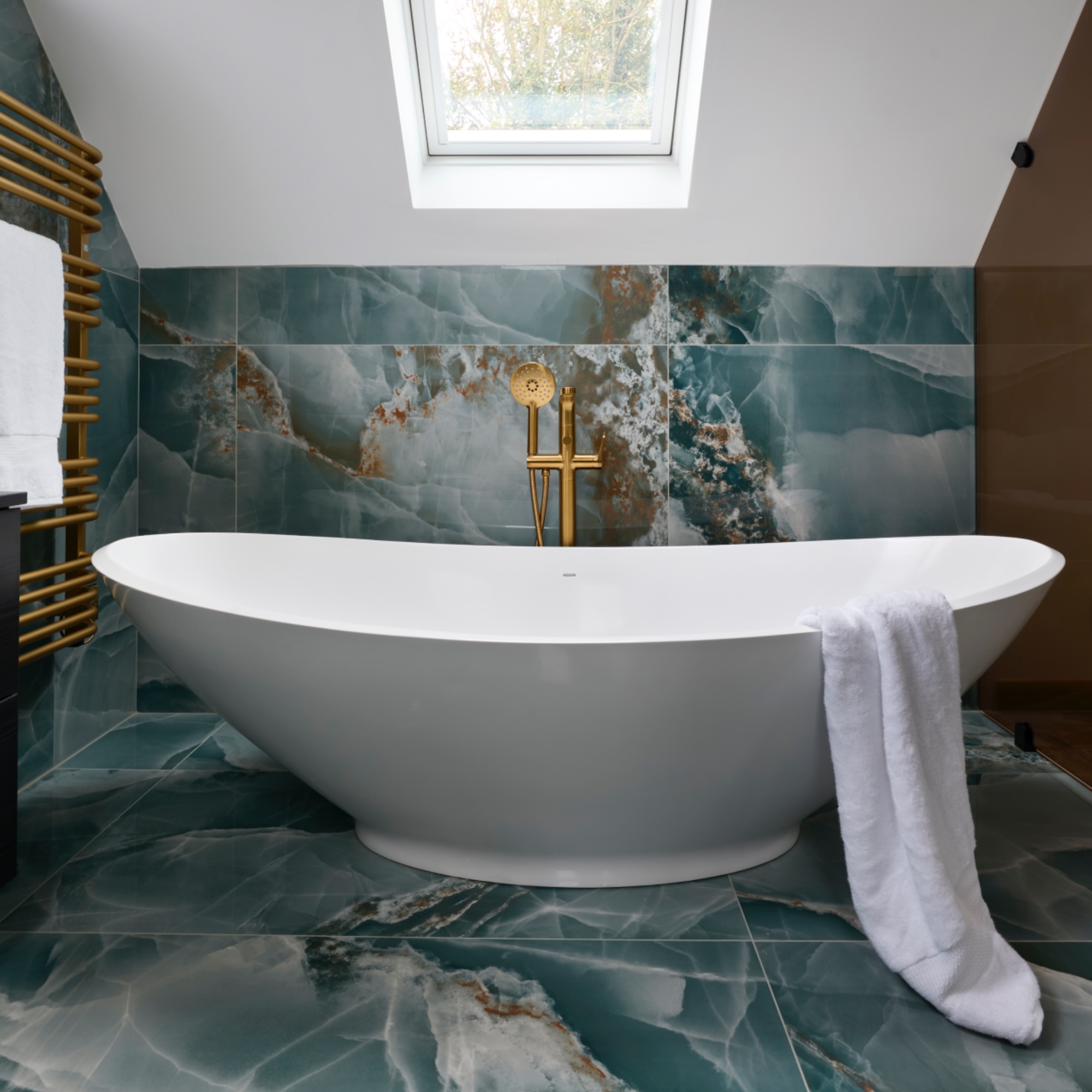 teal and white bathroom with teal marble floor and wall tiles, white modern bath, brassware