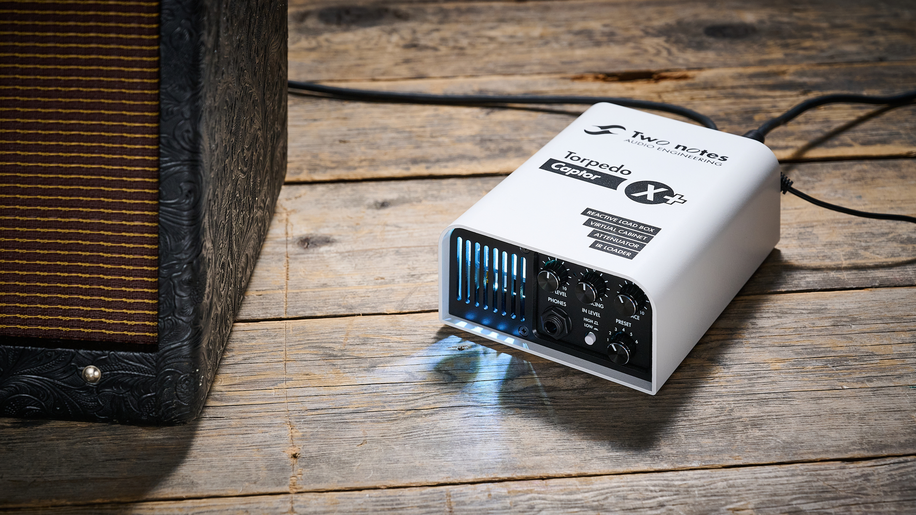 A Two Notes Torpedo Captor X Plus load box on a wooden floor next to a Fender tube amp