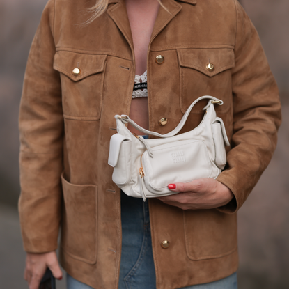 Sonia Lyson seen wearing Miu Miu white / black knit bra, Miu Miu brown suede leather jacket, Miu Miu white leather Pocket bag, Zara blue denim long skirt, on September 03, 2023 in Berlin, Germany. 