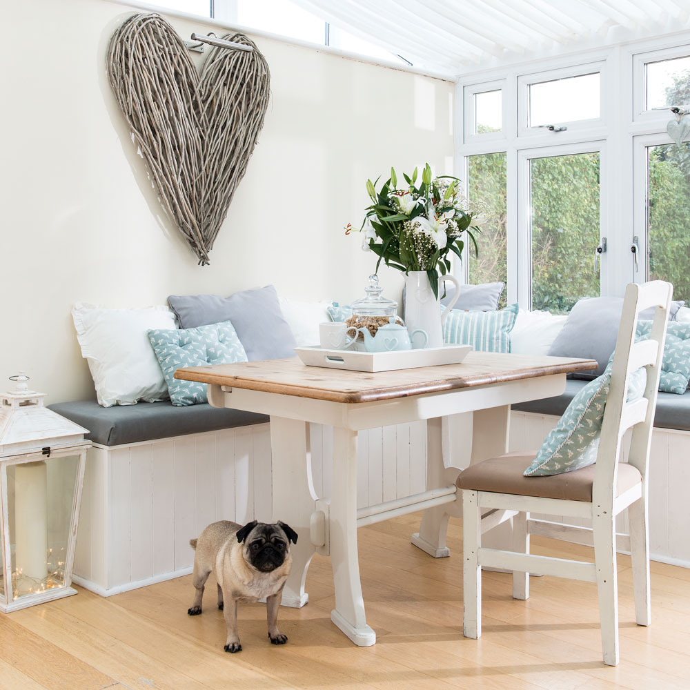 conservatory with dining table and chair and wooden floor and white wall and dog