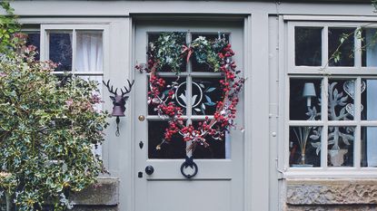 Christmas snowflake window decorations hang amongst green foliage 