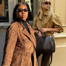Influencer Nnenna wears a suede long coat, a black East West bag, black slacks, and suede Adidas sneakers. Elsa Hosk wears an Alo bag with suede sneakers, brown leggings, and a beige jacket. 