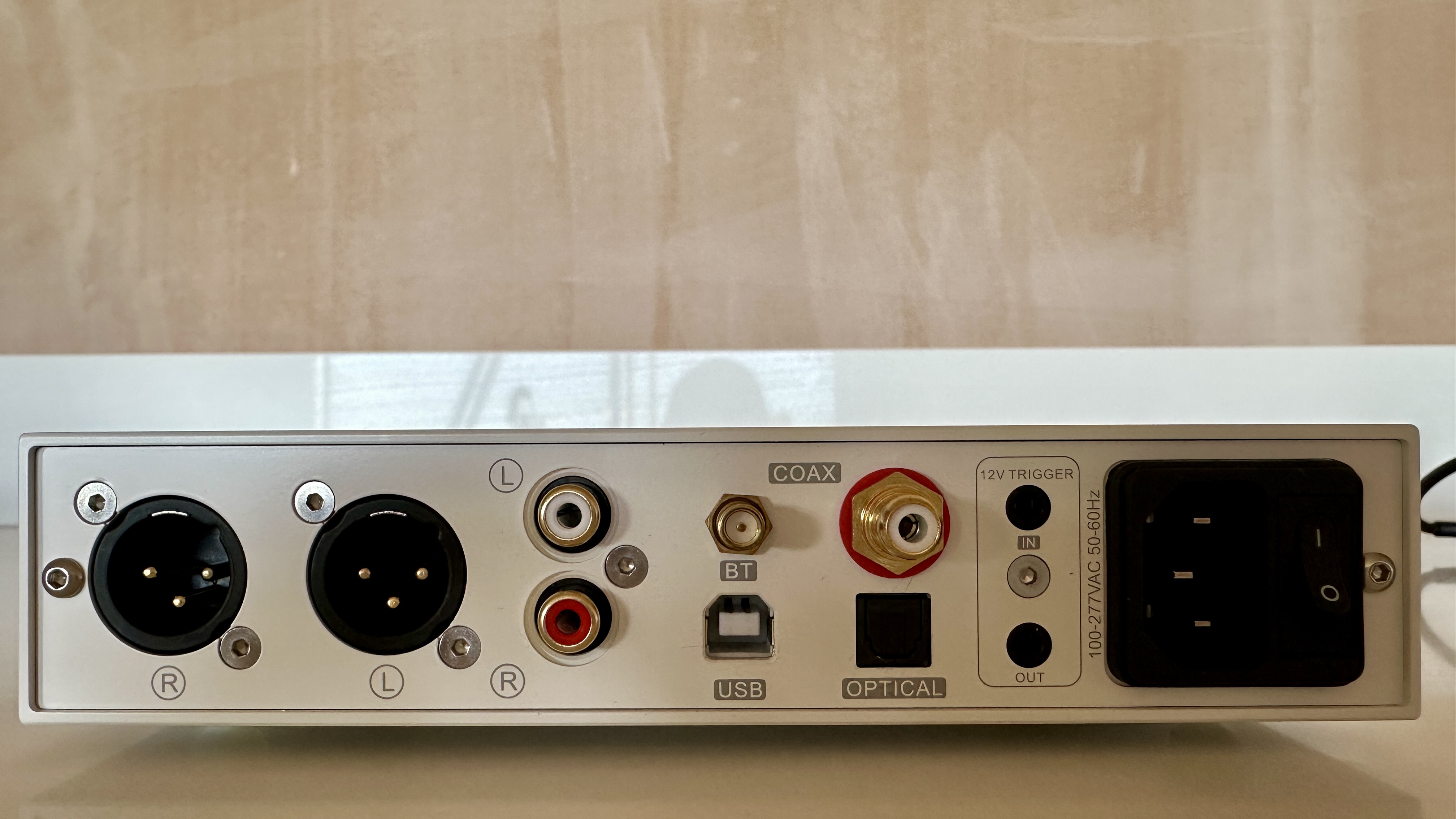 The Topping DX5 II on a light-wood table, showing the VU meter, ports and just-seen remote