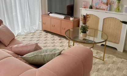 Pink velour 3-seater opposite TV on mid-century modern console, with light mustard yellow cushions and a dressed round glass coffee table