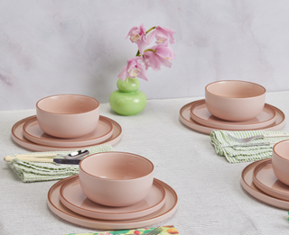 four sets of pink plates and bowl set out on a table with other tableware around