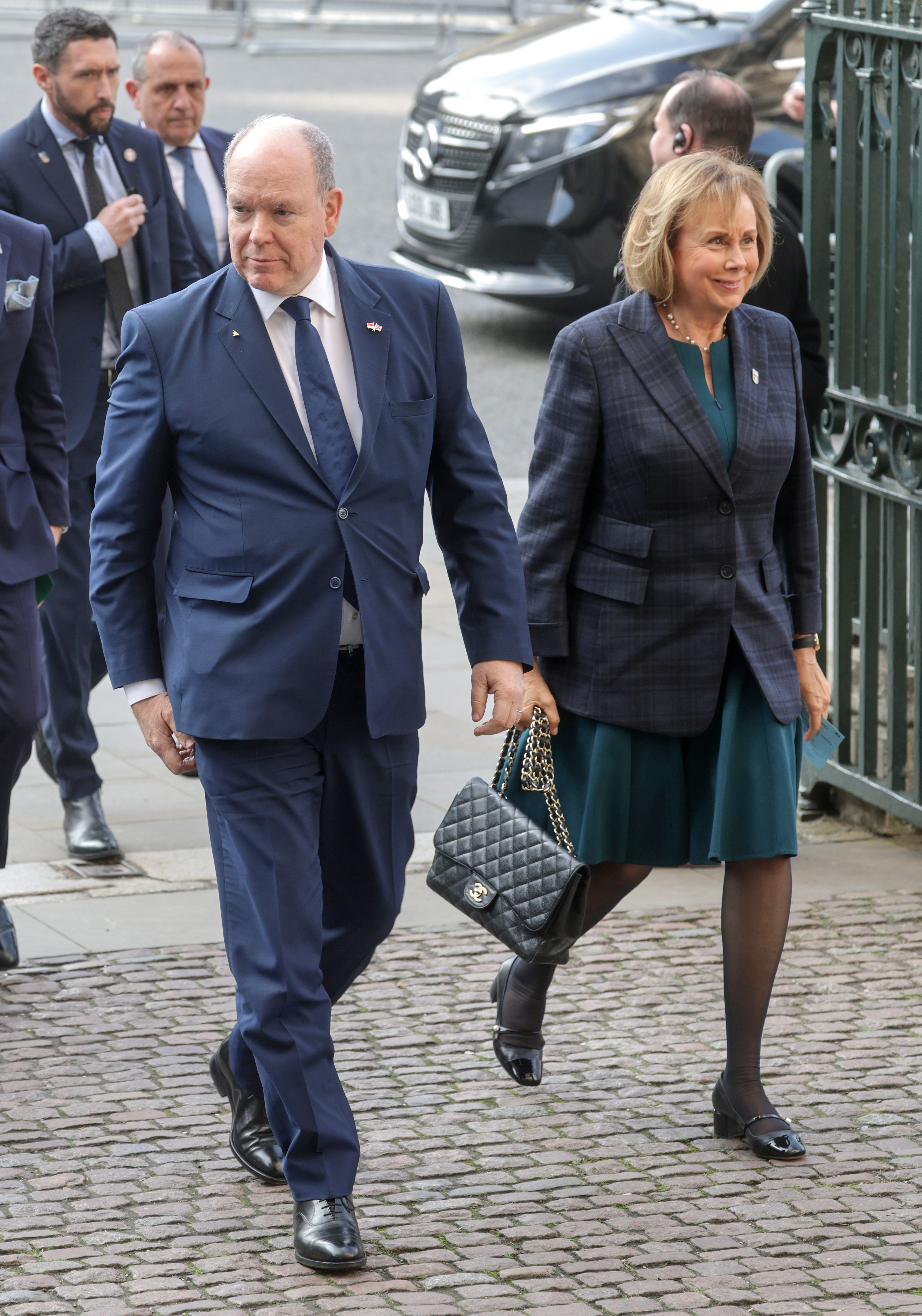 Prince Albert of Monaco wearing a blue suit walking next to a woman